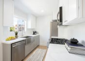 Thumbnail 3 of 32 - a white kitchen with stainless steel appliances and a window