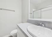 Thumbnail 48 of 49 - A white bathroom with a toilet, sink, and mirror.