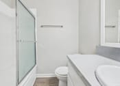 Thumbnail 49 of 49 - A white bathroom with a toilet, sink, and shower.