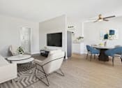 Thumbnail 42 of 49 - A living room with a white couch, a white chair, a black chair, a white coffee table, a black coffee table, a white TV, a white cabinet, a white plant, a white ceiling fan, a white wall, a