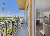 Thumbnail 8 of 36 - A balcony with a chair and a table overlooking a street.