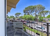 Thumbnail 7 of 36 - A balcony with a chair and a view of a parking lot.