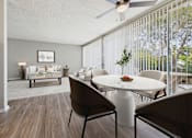 Thumbnail 3 of 36 - A living room with a white couch and a dining table with chairs.