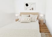 Thumbnail 21 of 32 - A bed with a white blanket and pillows with a painting on the wall.
