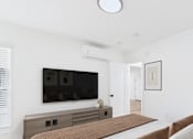 Thumbnail 3 of 32 - A modern bedroom with a large bed and a flat screen TV mounted on the wall.