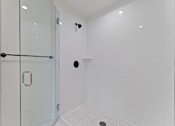 Thumbnail 101 of 119 - A white tiled bathroom with a glass shower door.