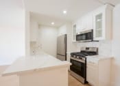 Thumbnail 7 of 28 - a kitchen with white cabinets and a stove and a refrigerator