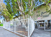 Thumbnail 30 of 33 - A white fence surrounds a building with a green sign that says Ques.
