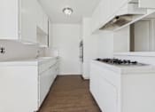 Thumbnail 22 of 33 - A white kitchen with wooden floors and white cabinets.
