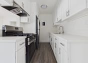 Thumbnail 11 of 33 - A modern kitchen with white cabinets and a black stove top oven.