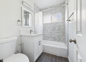 Thumbnail 20 of 33 - A white bathroom with a marble shower wall.