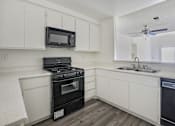 Thumbnail 24 of 35 - A kitchen with black appliances and white cabinets.