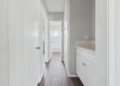 Thumbnail 38 of 75 - A long hallway with white walls and wood floors.