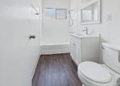 Thumbnail 42 of 75 - A white bathroom with a toilet, sink, and mirror.