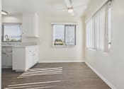 Thumbnail 46 of 75 - A kitchen with white cabinets and a window with blinds.