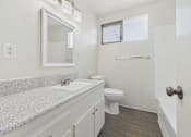 Thumbnail 58 of 75 - A bathroom with a granite countertop and white fixtures.