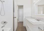 Thumbnail 59 of 75 - A white bathroom with a shower, sink and mirror.
