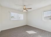 Thumbnail 23 of 38 - A room with a ceiling fan and two windows with blinds.