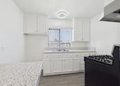 Thumbnail 25 of 38 - A kitchen with white cabinets and a black stove top oven.