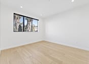 Thumbnail 110 of 119 - A room with wooden flooring and a window showing trees outside.