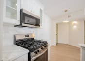 Thumbnail 8 of 28 - a kitchen with white cabinets and a stove and a microwave