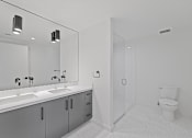 Thumbnail 39 of 119 - A white bathroom with a sink, mirror, and toilet.