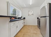 Thumbnail 2 of 41 - A kitchen with white cabinets and a black countertop.