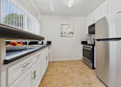 Thumbnail 1 of 41 - A kitchen with white cabinets and a stainless steel refrigerator.