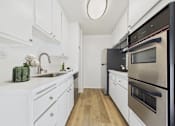 Thumbnail 1 of 72 - A modern kitchen with white cabinets and stainless steel appliances.
