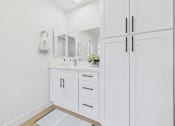 Thumbnail 19 of 95 - A white bathroom with a sink, mirror, and cabinets.