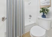 Thumbnail 20 of 95 - A white toilet sits next to a shower curtain in a bathroom.