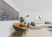 Thumbnail 16 of 95 - A modern living room with a brown chair and a white couch.