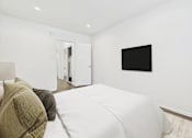 Thumbnail 26 of 95 - A bedroom with a bed and a television on the wall.
