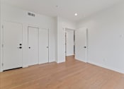 Thumbnail 100 of 119 - A room with white walls and wooden flooring with three doors.
