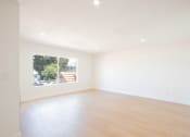 Thumbnail 9 of 28 - an empty living room with a window and wooden floors