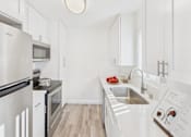 Thumbnail 30 of 81 - A modern kitchen with white cabinets and stainless steel appliances.