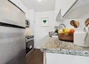 Thumbnail 2 of 81 - A kitchen with a granite countertop and a refrigerator.
