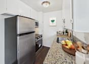 Thumbnail 1 of 81 - A kitchen with a granite countertop and a black refrigerator.