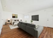 Thumbnail 18 of 81 - A grey couch is in the middle of a white room with a bed and a television.