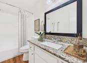 Thumbnail 21 of 81 - A bathroom with a marble countertop and a white toilet.
