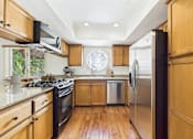 Thumbnail 4 of 24 - A kitchen with wooden cabinets and a stainless steel refrigerator.