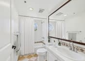 Thumbnail 14 of 24 - A white bathroom with a toilet, sink, and shower.