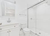 Thumbnail 32 of 35 - A white bathroom with a toilet, sink, and shower.