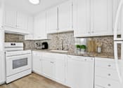 Thumbnail 9 of 35 - A kitchen with white cabinets and appliances.