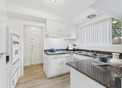 Thumbnail 1 of 16 - A kitchen with white cabinets and a black countertop.