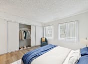 Thumbnail 5 of 16 - A bedroom with a bed, pillows, a chair, and a wardrobe.
