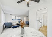 Thumbnail 2 of 16 - A living room with a white ceiling fan and a grey sofa.