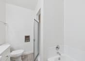 Thumbnail 7 of 16 - A white bathroom with a toilet, sink, and bathtub.