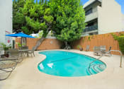 Thumbnail 9 of 17 - a swimming pool with chairs and umbrellas in front of a building