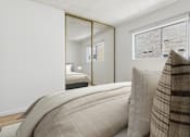 Thumbnail 7 of 29 - A bedroom with a large bed and a mirror on the wall.